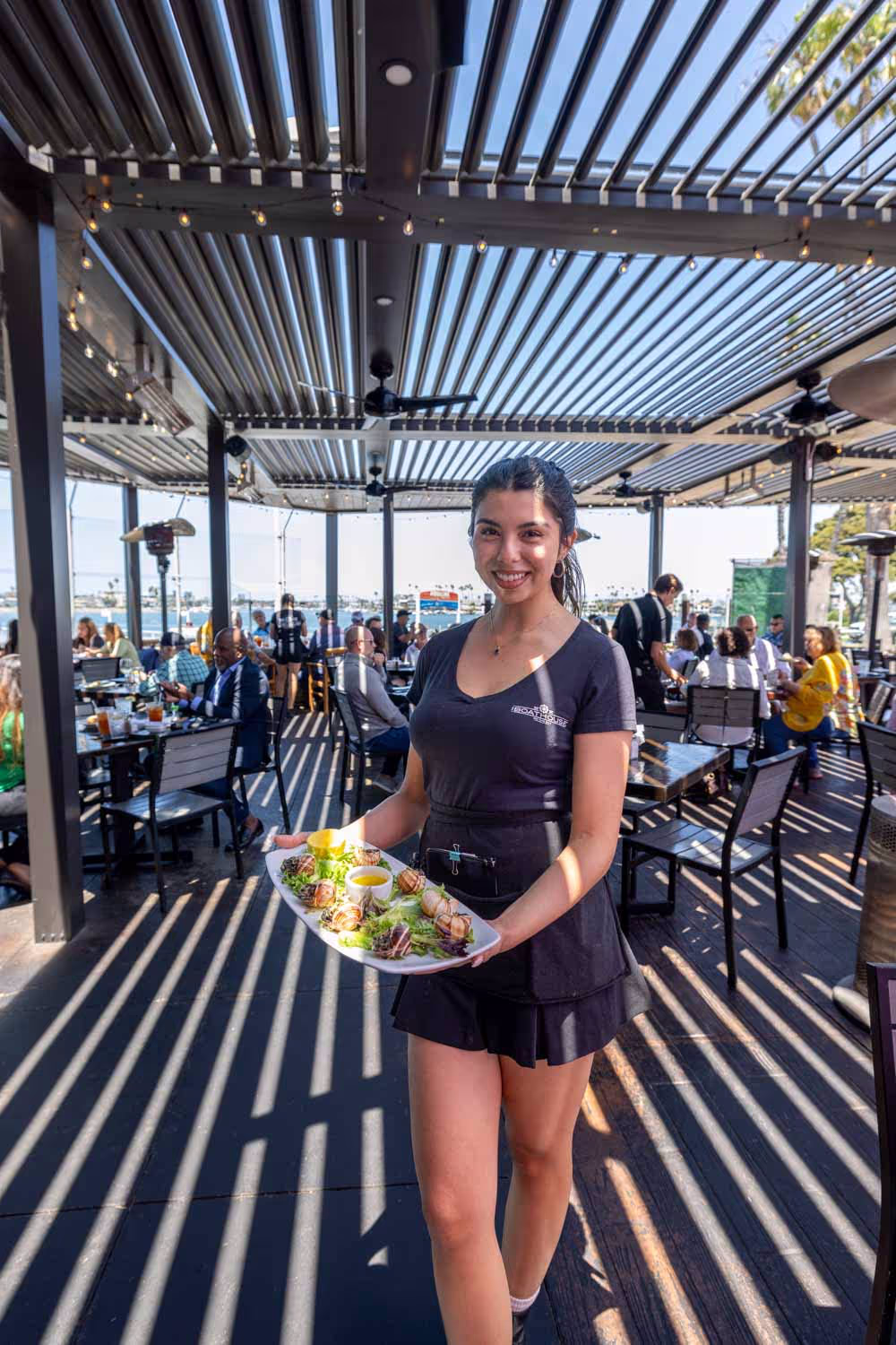 Server presenting dishes on the Boathouse patio