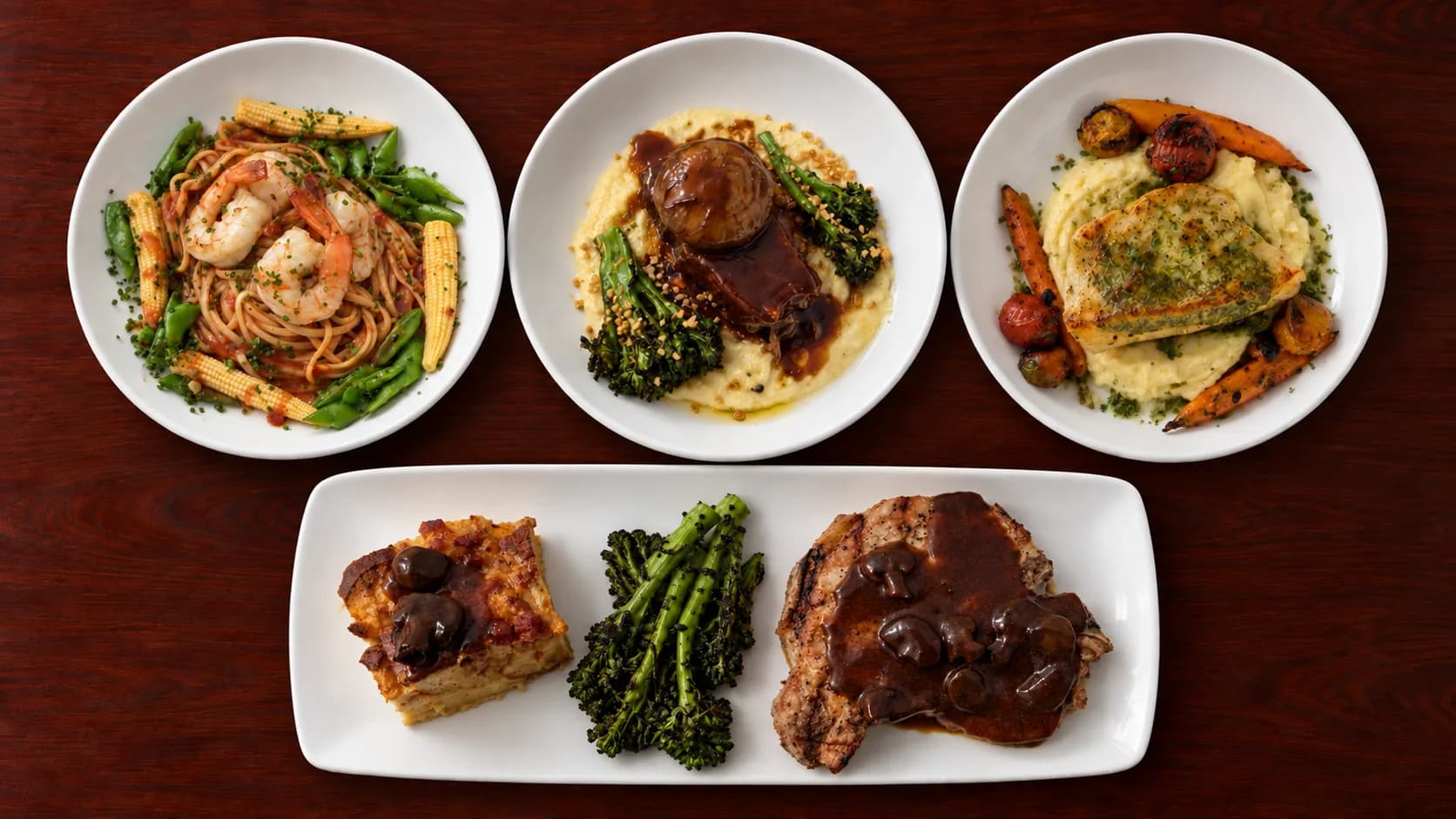 Mum’s four specials on a dark wood table: ginger shrimp linguine, braised short rib and halibut in white bowls, with grilled pork chop, broccolini and chorizo bread pudding on a long rectangular plate.